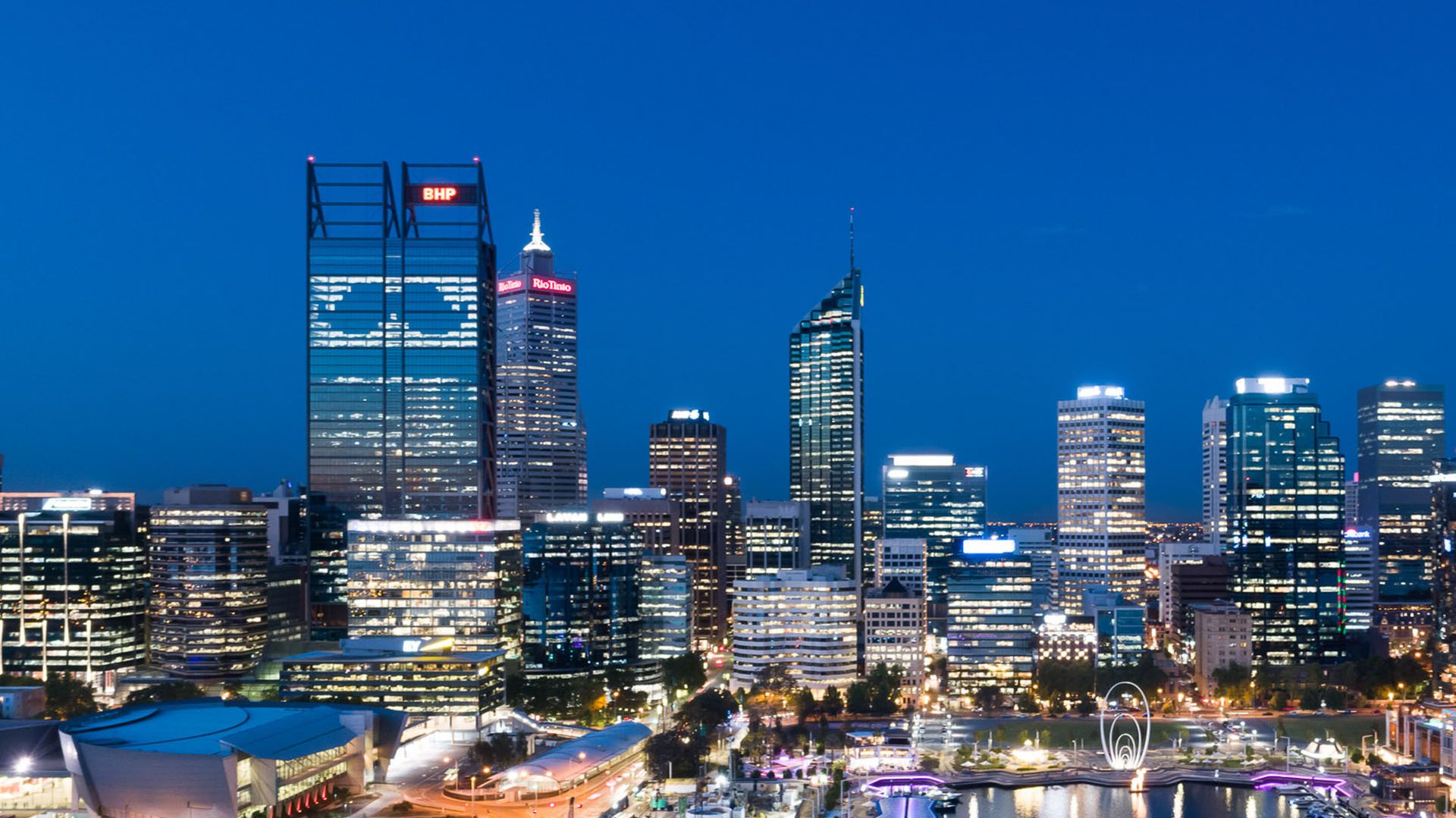 Night-time view of the Perth CBD skyline. The Movember logo is visible in the BHP building.